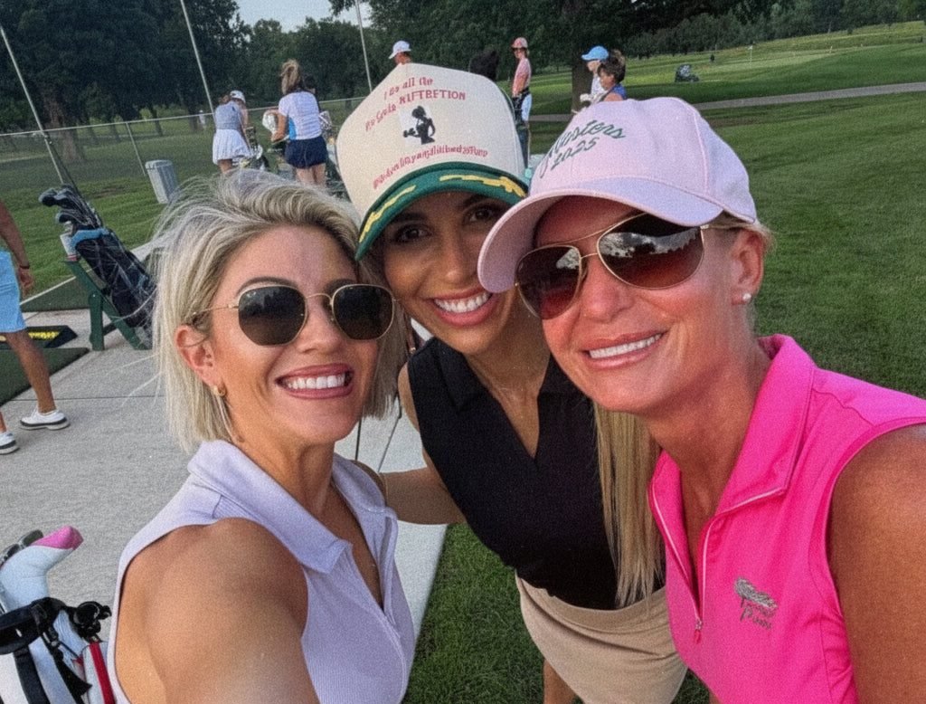 Three Girly Pop members in caps and sunglasses, arms around each other beside the carts at a range night.