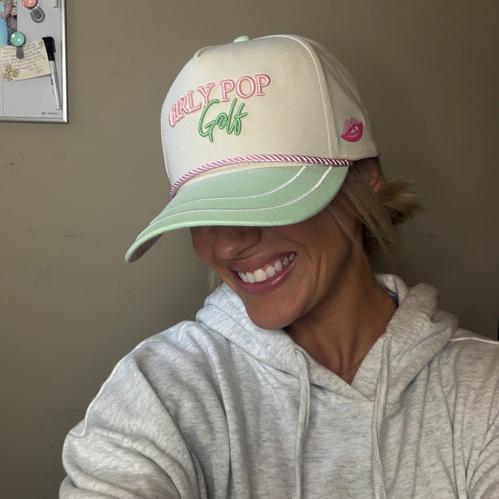 A Girly Pop member laughing in a cream cap after a range night.